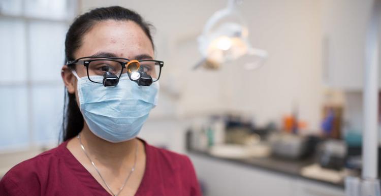female dentist wearing pink scrubs and a face covering