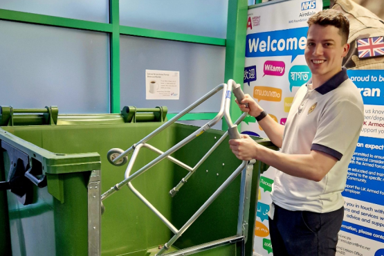 Photograph of a person putting a walking aid into one of the recycling bins